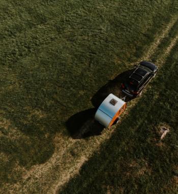 Woody Teardrop-Trailer hinter Auto aus der Luft