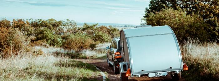 Rebel Teardrop-Trailer hinter einem SUV bei der Fahrt durch unwegsames Gelände